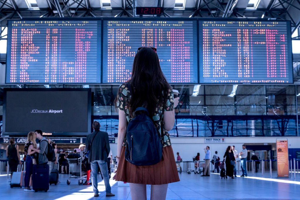 A woman stands in a busy airport, much like Orlando International Airport (MCO)